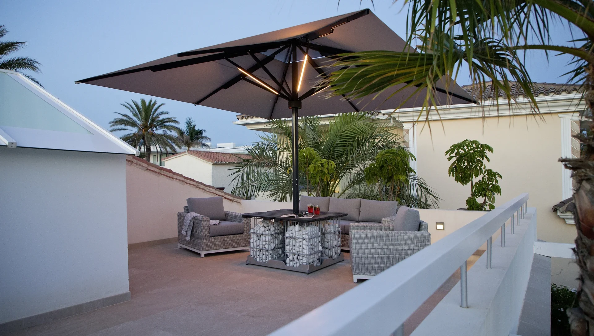 Moderne Dachterrasse mit stilvollen Möbeln und großem Sonnenschirm bei Abenddämmerung